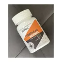 Frasco de Bionica con etiqueta naranja y negra, recostado sobre un sillón gris