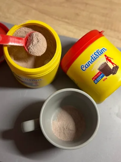 Bote abierto de CandiSlim con el cacito y una taza con el polvo