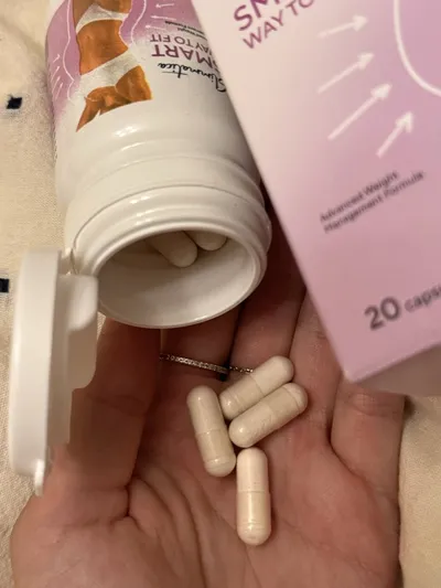Cápsulas de Slimmatica de color crema en la palma de una mano, junto al bote abierto